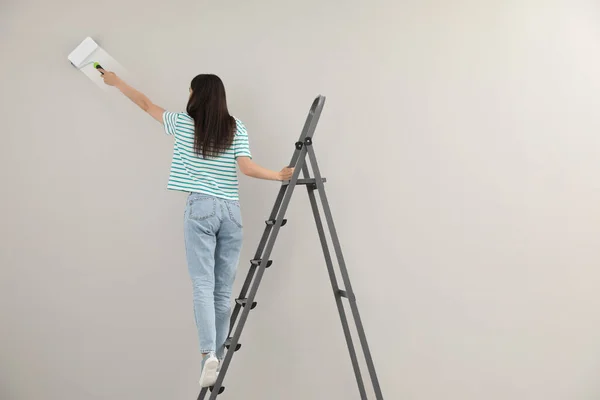 Young Woman Painting Wall Roller Ladder Back View — Stock Photo, Image
