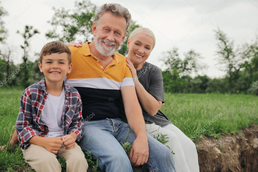 Cute little boy and grandparents spending time together in park