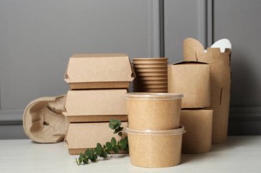 Tek kullanımlık çevre dostu ürünler beyaz ahşap masada.