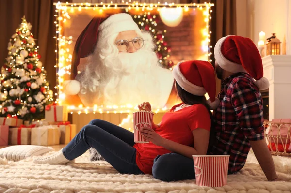 Couple watching movie on projection screen in room decorated for Christmas
