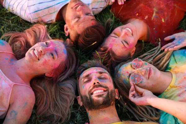 快乐的朋友们在户外绿草上涂满了五彩缤纷的粉末染料 Holi节庆祝活动 — 图库照片