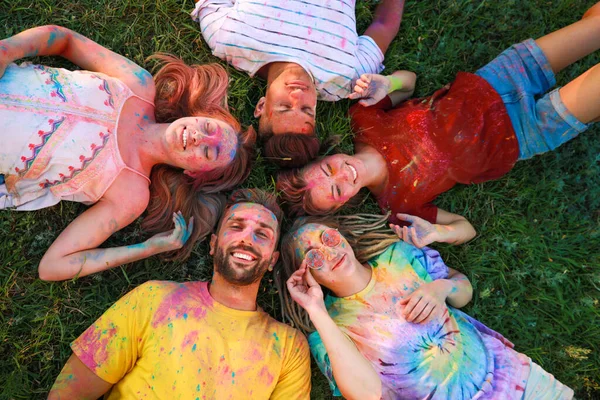 快乐的朋友们在户外绿草上涂满了五彩缤纷的粉末状染料 Holi节庆祝活动 — 图库照片