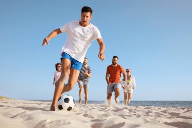 Sahilde futbol oynayan bir grup arkadaş.