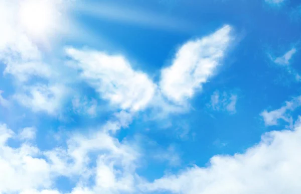 Silhouette of angel\'s wings made of clouds in blue sky