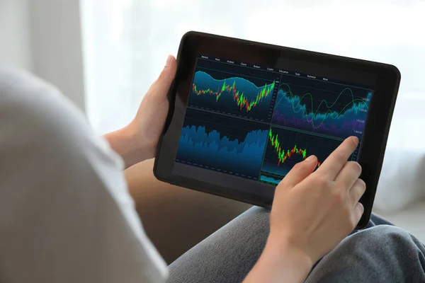 Woman analyzing electronic trading platform on tablet indoors, closeup. Stock exchange