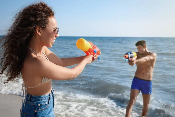 ビーチで楽しい水銃を持つカップル — ストック写真