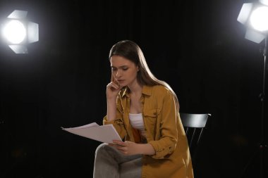 Tiyatroda prova sırasında senaryosunu okuyan profesyonel bir aktris.