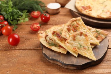 Tahta masada peynir, dereotu ve domatesle lezzetli bir khachapuri kes.