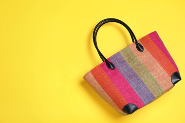 Sarı arka planda şık çizgili plaj çantası, üst manzara. Metin için boşluk