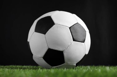 Siyah arka plana karşı yeşil çimlerde futbol topu