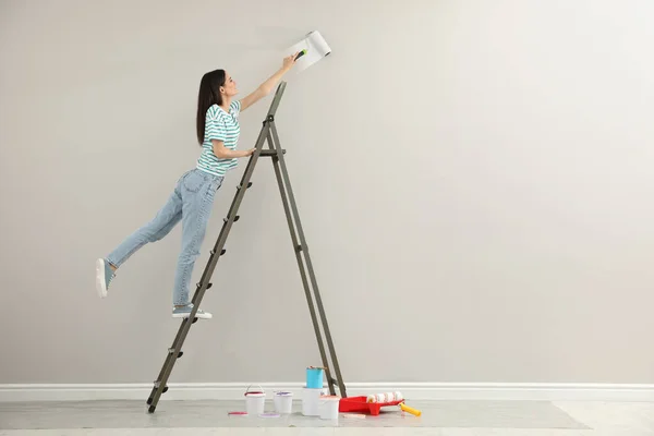 Junge Frau Bemalt Wand Mit Roller Auf Leiter Drinnen Raum — Stockfoto