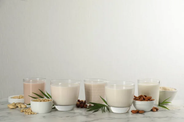白い大理石のテーブルの上に異なるビーガンミルクと成分 テキストのスペース — ストック写真