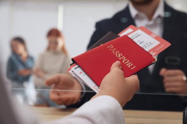 Havaalanındaki kayıt masasında biletlerle birlikte pasaport veren ajan.