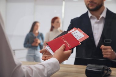 Havaalanındaki kayıt masasında biletlerle birlikte pasaport veren ajan.