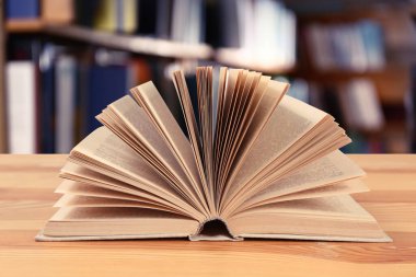 Kütüphanedeki ahşap masanın üzerinde açık bir kitap
