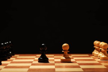 Siyah arkaplanda oyun taşları olan satranç tahtası