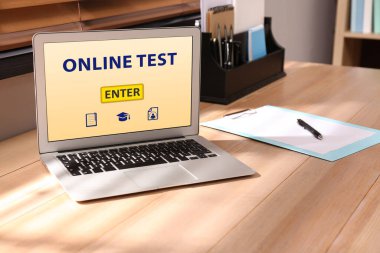 Ofisteki ahşap masada çevrimiçi test edilen dizüstü bilgisayar.