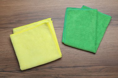 Ahşap masa üzerinde yeşil ve sarı mikrofiber kumaşlar, düz yatıyordu.