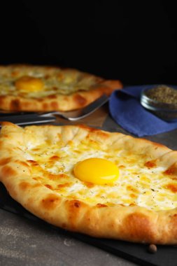 Gri masada peynirli ve yumurtalı taze ev yapımı khachapuri, yakın plan.