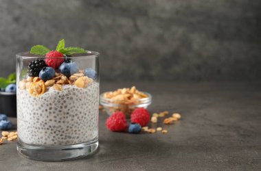 Böğürtlenli lezzetli chia pudingi, granola ve nane şekeri gri masada, mesaj için yer var.