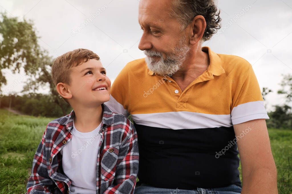 Cute little boy and grandfather spending time together in park