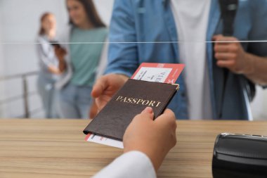 Havaalanındaki kayıt masasında biletle pasaport veren ajan, yakın plan.