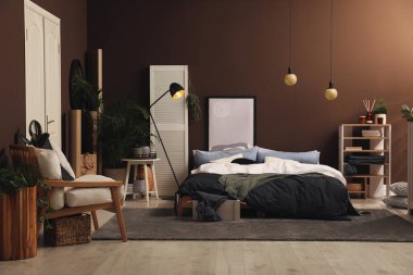 Kahverengi duvarın yanında büyük yataklı şık bir oda.