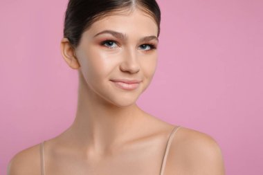 Pembe arka planda güzel bir kız. Güzel bir yüz, pürüzsüz bir ten.