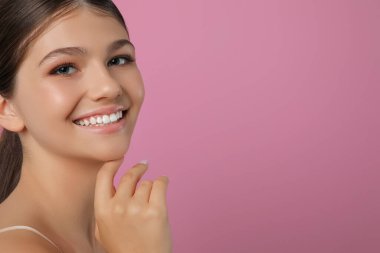 Pembe arka planda güzel bir kız, mesaj için yer var. Güzel bir yüz, pürüzsüz bir ten.