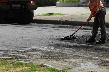 Şehir caddesinde yeni asfalt döşeyen işçiler, yakın plan. Yol onarım servisi