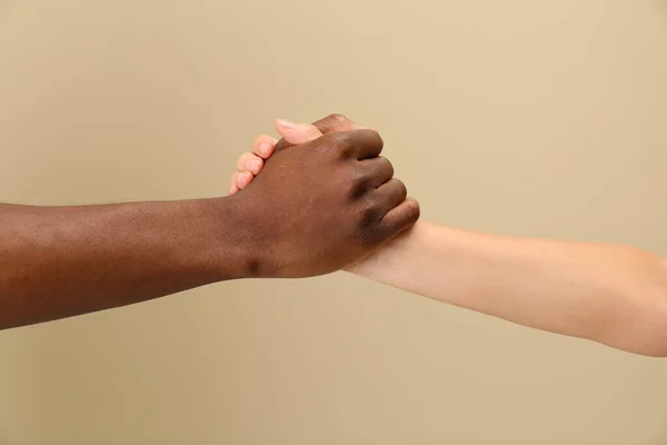 女性とアフリカ系アメリカ人男性はベージュの背景に手を握りしめ クローズアップ — ストック写真