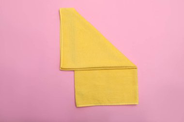 Pembe arka planda katlanmış sarı plaj havlusu, üst manzara.