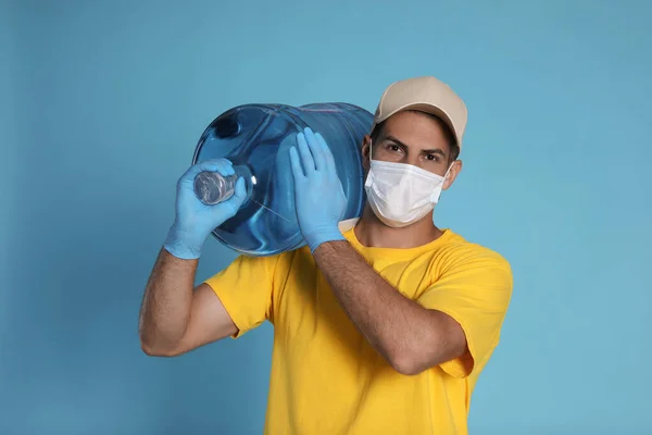 Kurir Medicinsk Mask Håller Flaska För Vattenkylare Ljusblå Bakgrund Leverans — Stockfoto