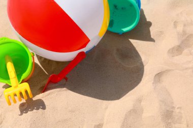 Farklı plaj oyuncakları ve kumda şişme top, mesaj için yer.