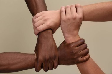 Men joining hands together on beige background, closeup clipart