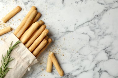 Lezzetli Grissini çubukları ve biberiye beyaz mermer masada, düz yerde. Metin için boşluk