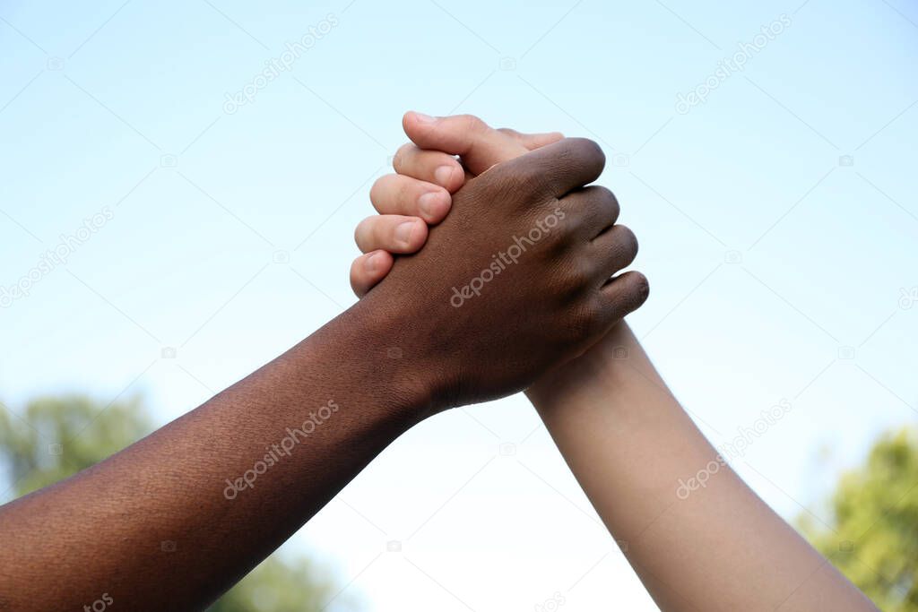 Closeup view of men clasping hands outdoors