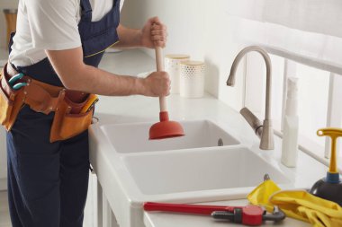 Tesisatçı lavabonun tıkanmasını açmak için lavabo pompası kullanıyor.