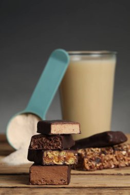 Farklı enerji çubukları, protein kokteyli ve tahta masanın üzerindeki toz.