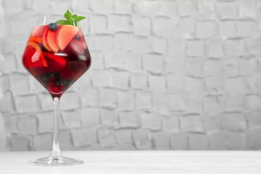 Beyaz ahşap masada meyveli bir bardak Red Sangria.