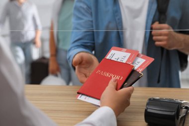 Havaalanındaki kayıt masasında biletlerle birlikte pasaport veren ajan.