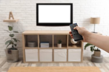 Genç adam TV 'de uzaktan kumandayla kanal değiştiriyor.