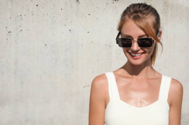 Güneşli bir günde dışarıda güneş gözlüklü güzel bir kadın, mesaj atmak için uygun bir yer.