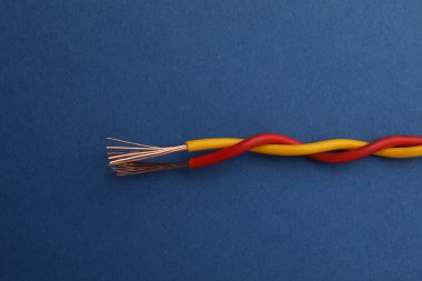 Mavi arka planda iki bükülmüş elektrik kablosu, yakın plan.