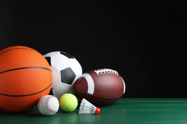 Yeşil ahşap yüzeyde farklı spor topları ve mekik horozu. Metin için boşluk