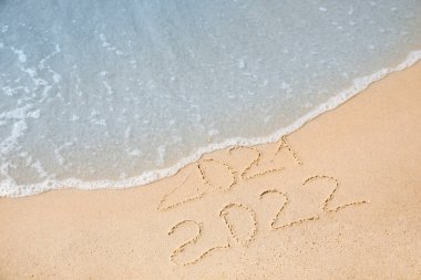 Kumlu sahilde yazılmış tarihler. 2021 deniz dalgalarıyla yıkandı ve 2022 yılı yaklaşıyor.