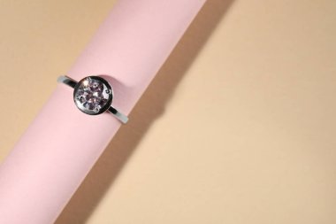 Bej arka planda değerli taşlı güzel bir nişan yüzüğü, üst manzara. Metin için boşluk