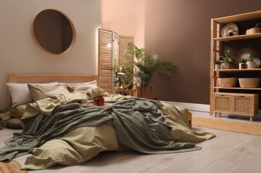 Geniş konforlu yatağı ve saksısı olan şık bir iç mekan.