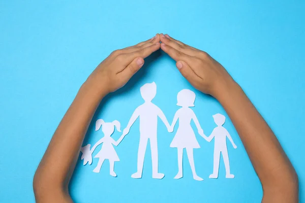 Kind Deckt Familienfiguren Aus Papier Mit Den Händen Auf Hellblauem — Stockfoto