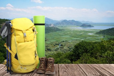 Ahşap yüzeyde turistler için kamp malzemeleri ve güzel dağ manzarası.